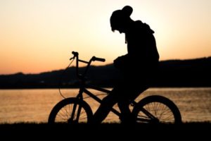 Teen riding bicycle in sunset