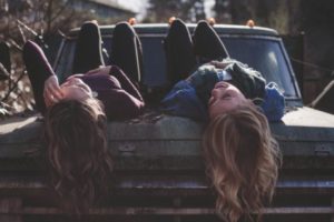 Teen or millennial girls laying on car hood