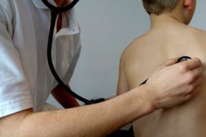 Doctor using stethoscope to listen to boy
