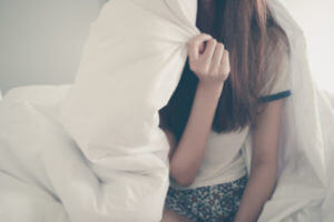 Teen girl hiding under covers