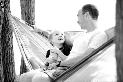 Dad sitting in hammocks with son