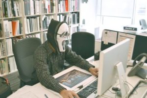 Man wearing Scream mask at office desk