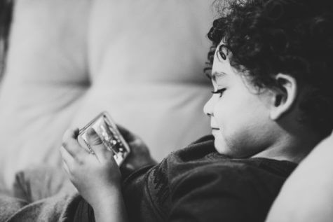 Child laying on couch with phone