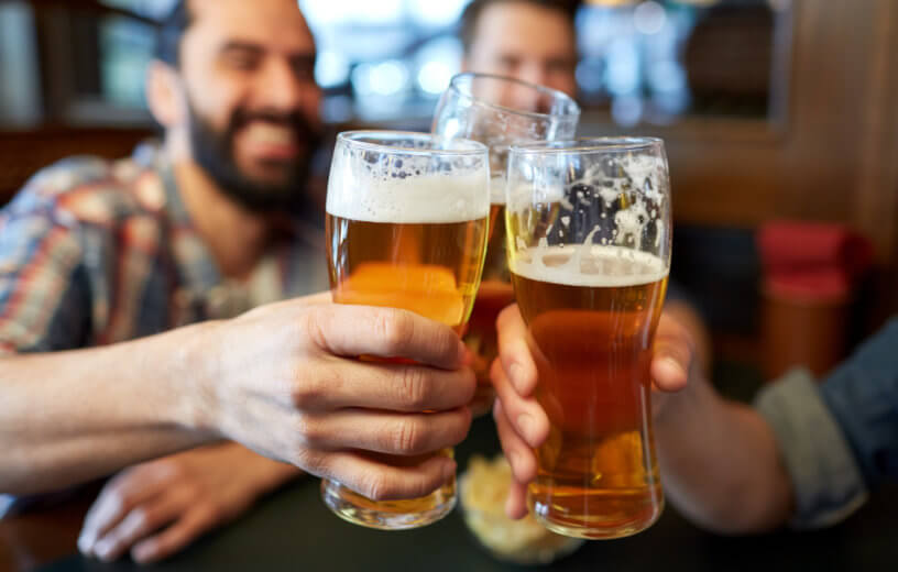 Men drinking beer, having toast at bar