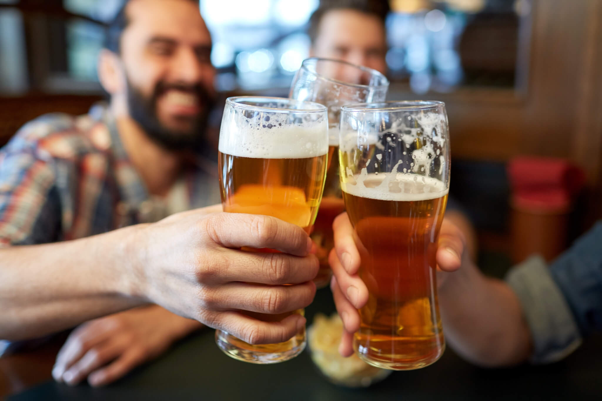 Men drinking beer, having toast at bar