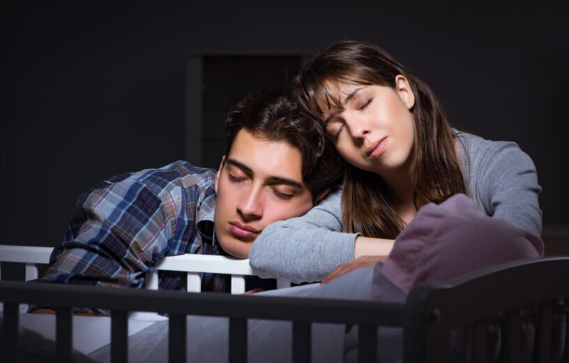 New parents sleeping on baby's crib