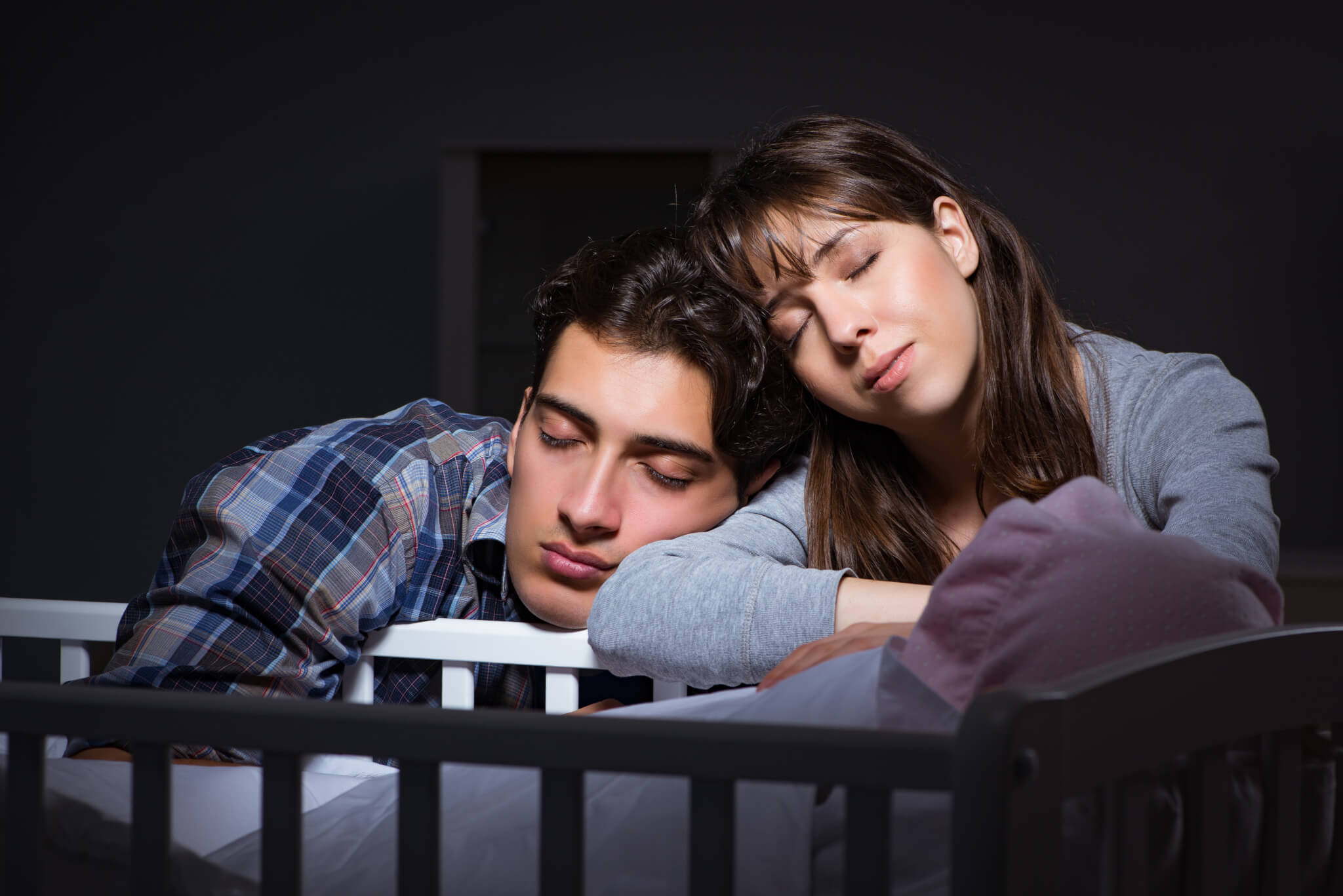 New parents sleeping on baby's crib