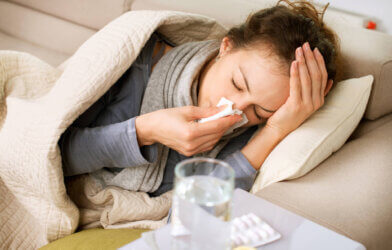 Sick woman blowing nose, has common cold and flu symptoms