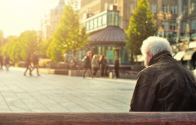Older, retired person sitting alone on a bench