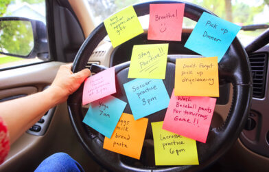 Person with busy to-do list, post-it notes on steering wheel