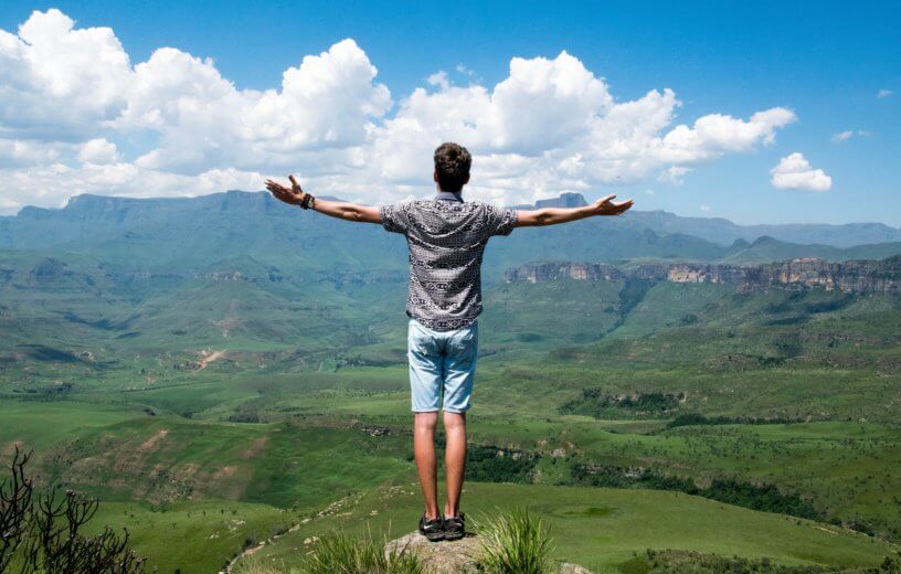 Man with open arms looking at beautiful nature scene