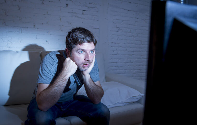 Man sitting on couch watching television
