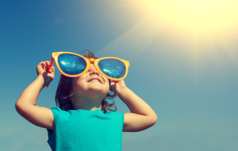 Happy little girl with big sunglasses looking at the sunshine