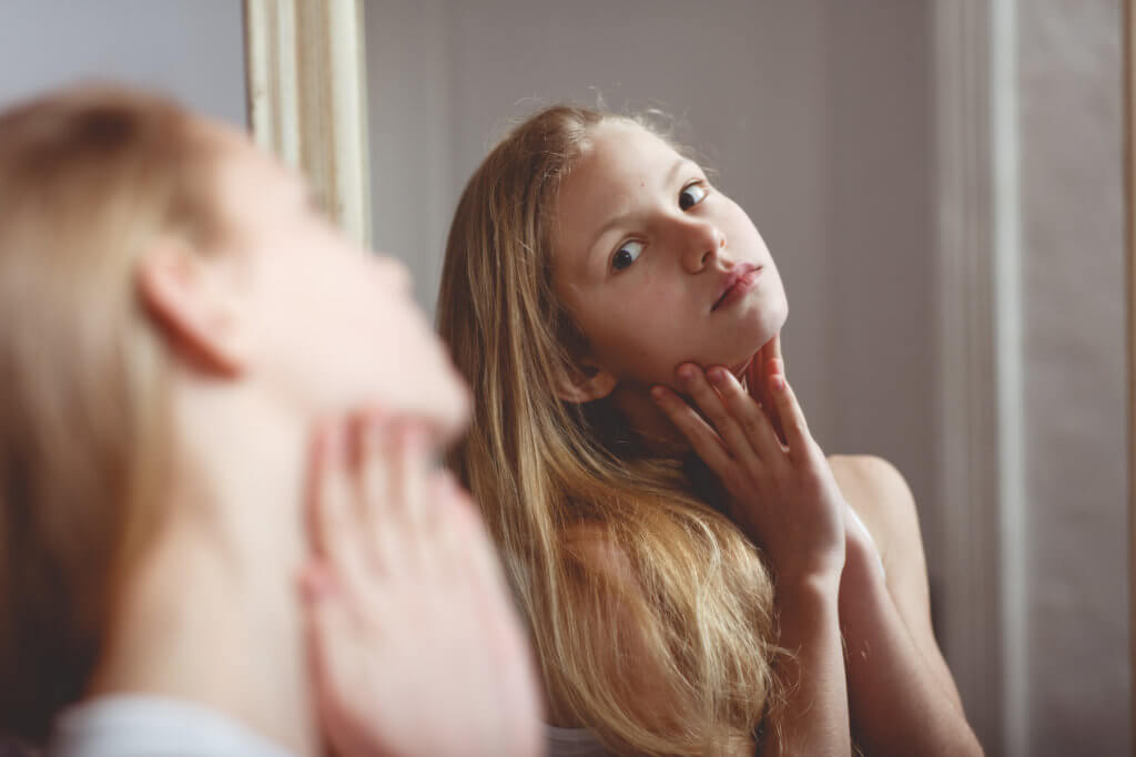 Young girl or teen looking at herself in the mirror