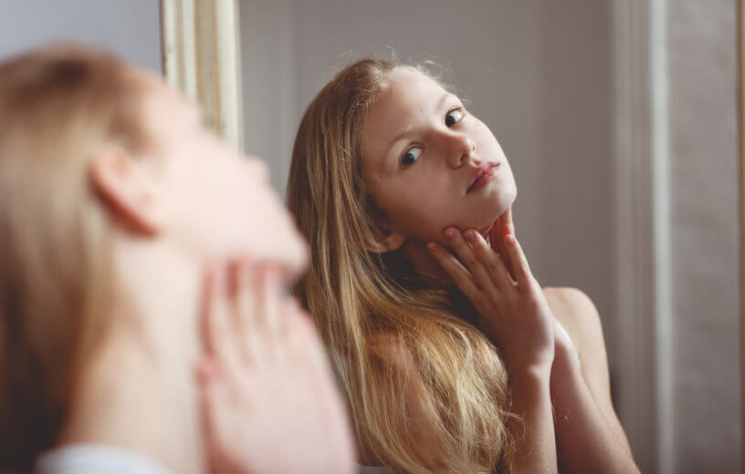 Young girl or teen looking at herself in the mirror