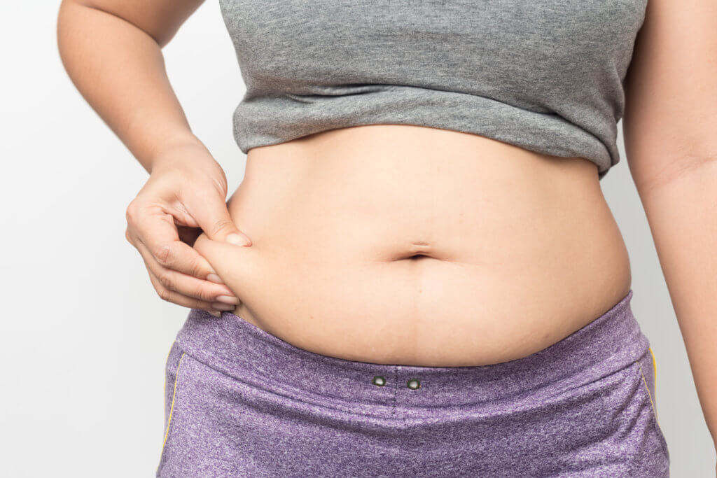 Overweight woman hand pinching excessive belly fat