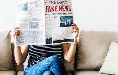 Woman reading 'Fake News' newspaper
