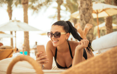 Woman on vacation using phone while lying on a beach