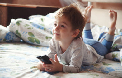 Little boy watching TV in bed
