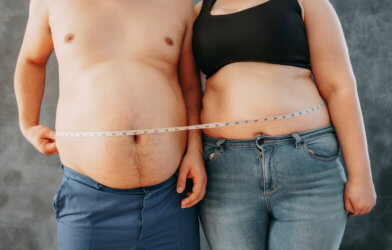 Obese or overweight couple standing together wrapped with waist measure tape