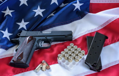 Gun with ammo on an American flag: gun control and gun rights debate