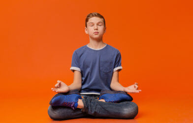 Boy sitting on floor practicing mindfulness meditation
