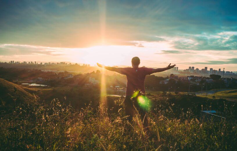 Man filled with awe, arms wide open at sunset