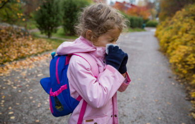 Sick little girl blowing nose while on her way to school