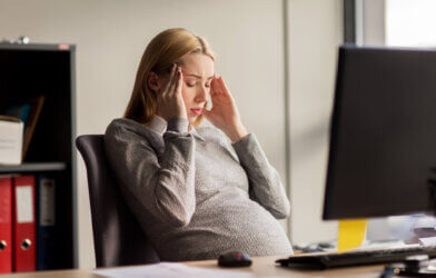 Pregnant woman at office feeling stressed, sick
