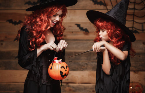 Mom and daughter dressed up as witches on Halloween holding candy