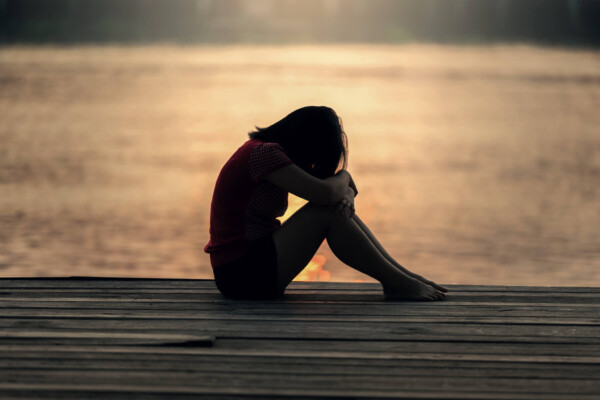 Sad young woman or teen girl alone on pier