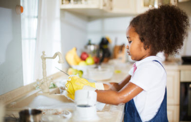Young child washing dishes, doing chores
