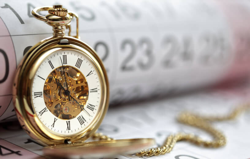 Time: Gold pocket watch on top of calendar