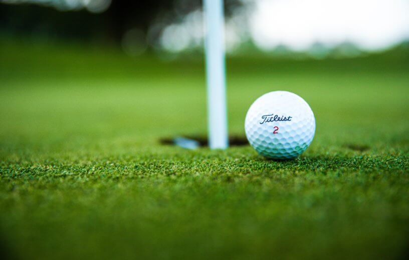 Golf ball next to hole