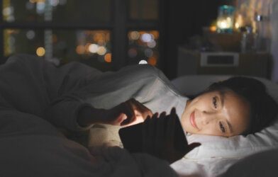 Woman looking at phone in bed, blue light in face