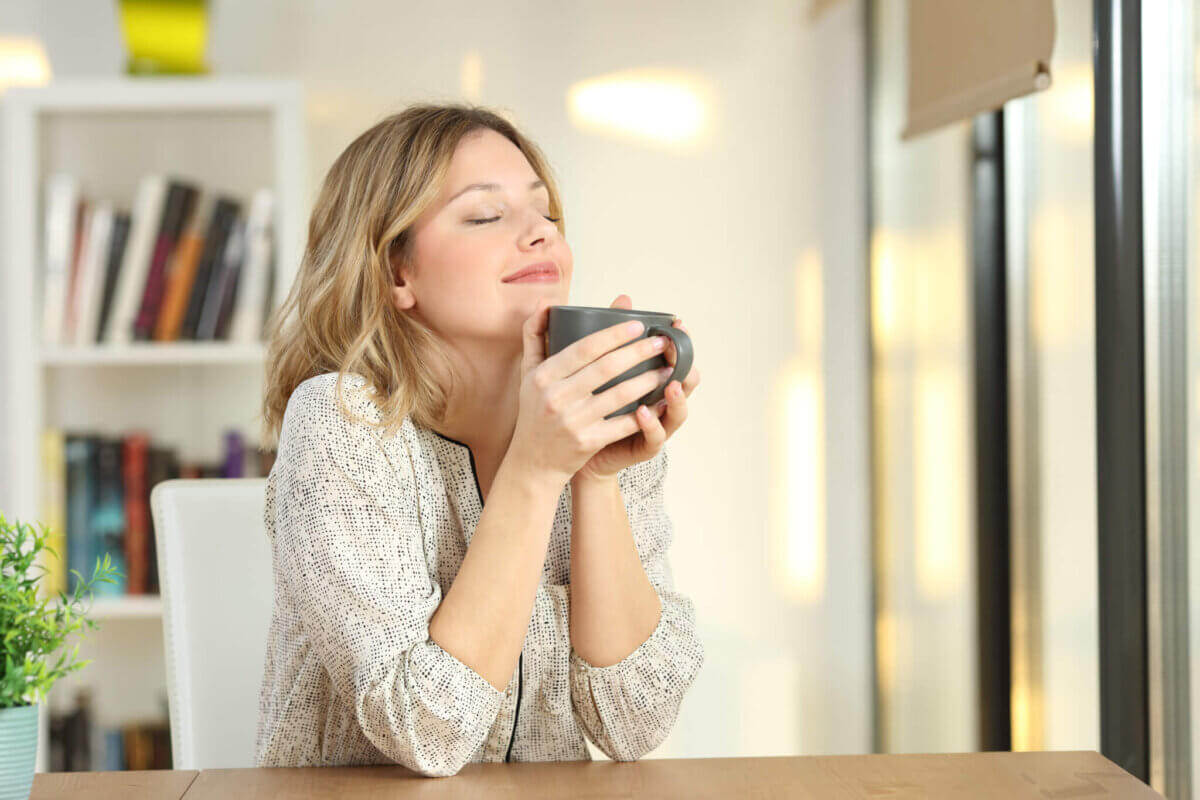 Woman smiling as she drinks a cup of coffee or tea