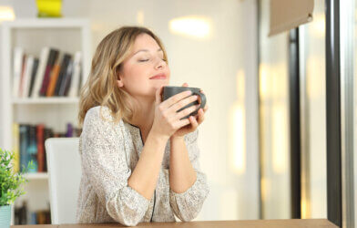 Woman smiling as she drinks a cup of coffee or tea