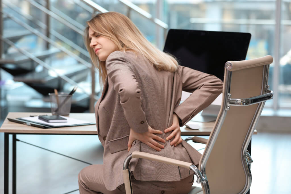Woman battling lower back pain at office