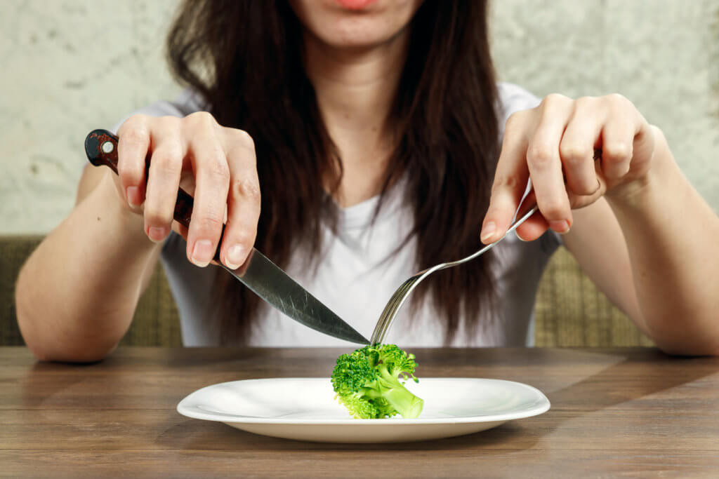 Woman on diet eating broccoli on plate