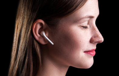 Woman listening to wireless earphones, doing mindfulness meditation