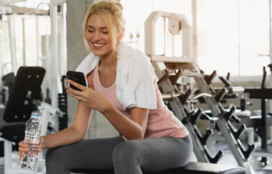 Woman using phone while exercising at gym