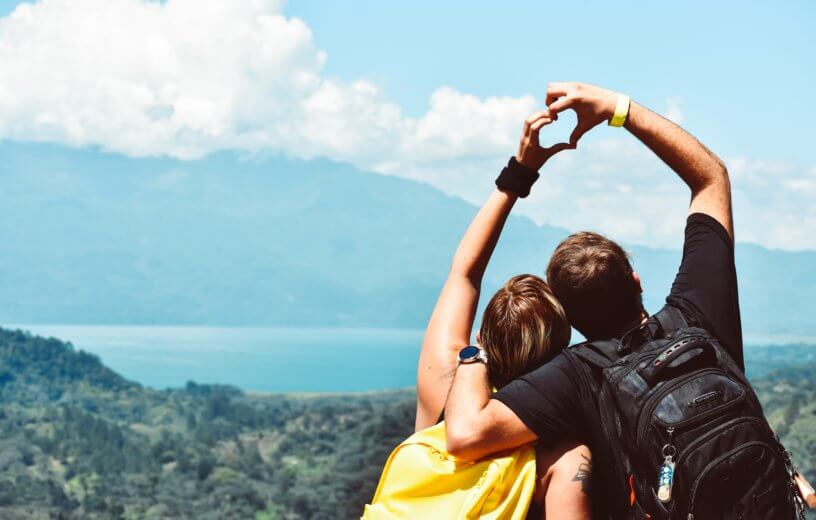 Couple making heart shape with hands on mountain