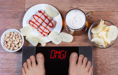 Weight gain: Scale says "OMG" with snacks around it