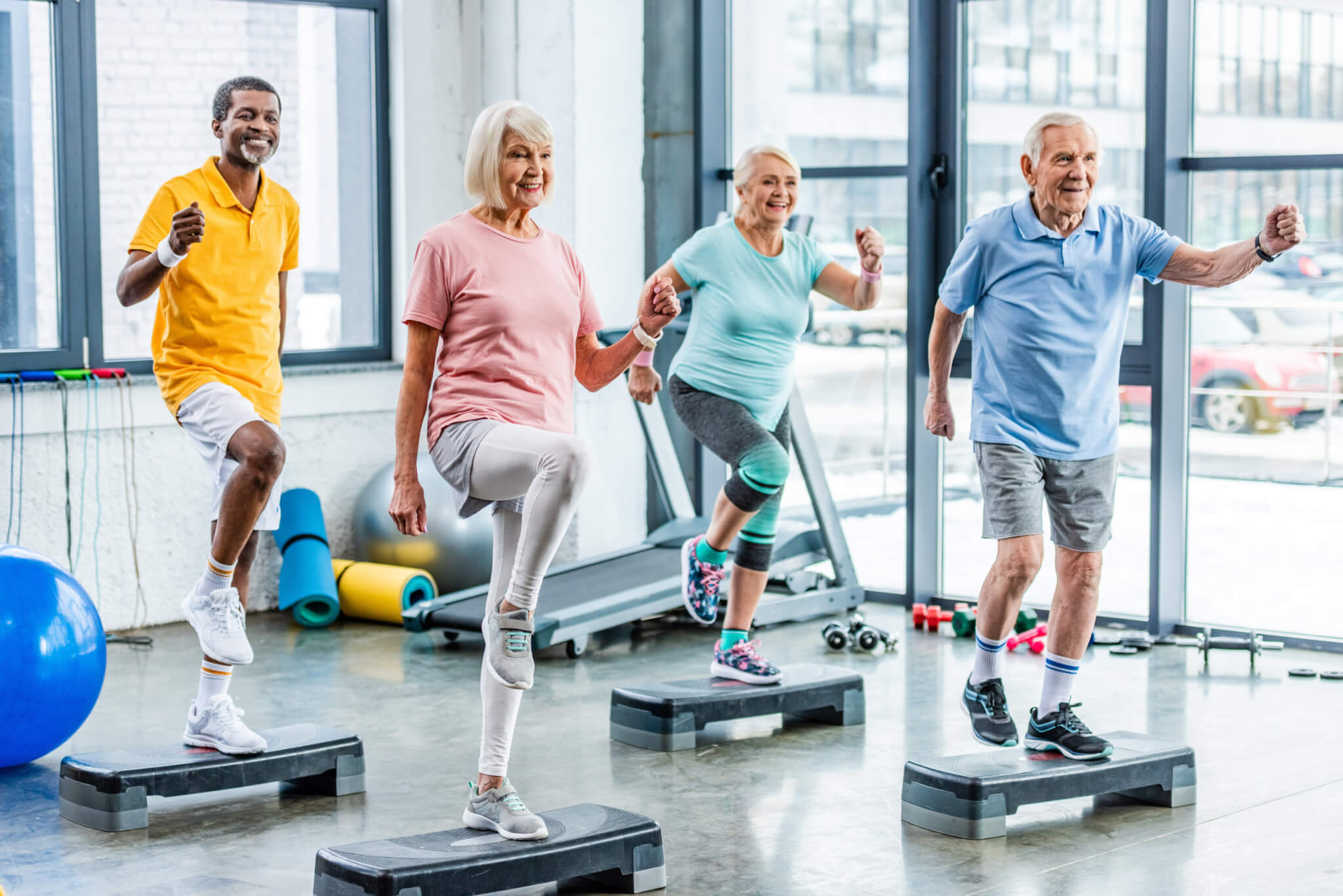 Personas mayores haciendo clases de ejercicio aeróbico en el gimnasio.