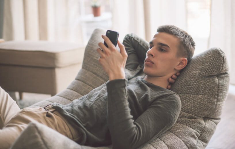 Teen sitting on couch looking at smartphone