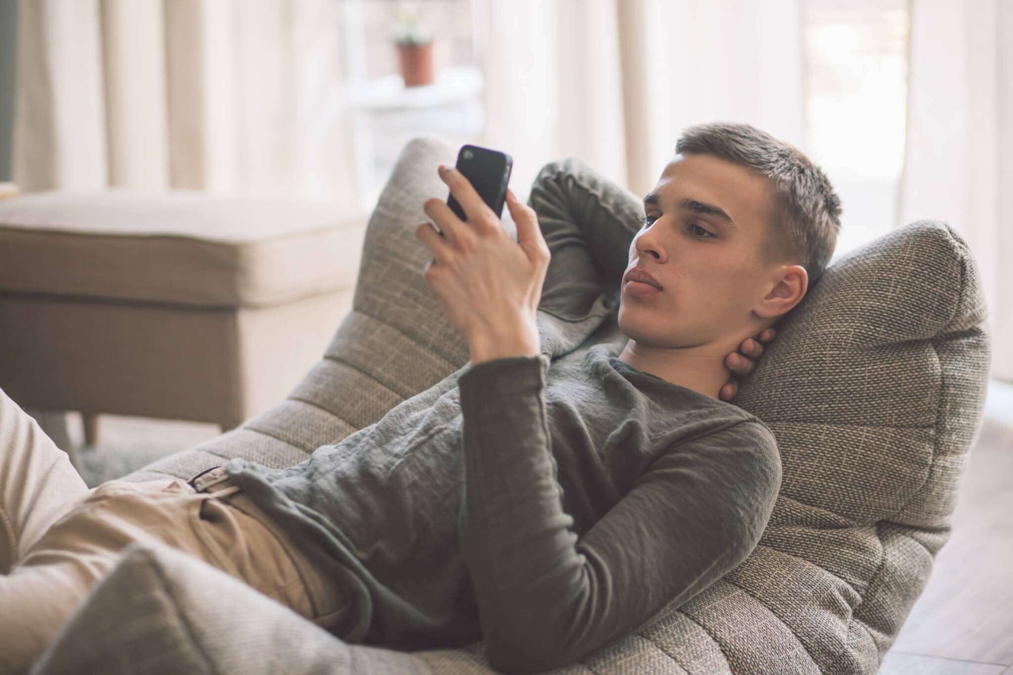 Teen sitting on couch looking at smartphone