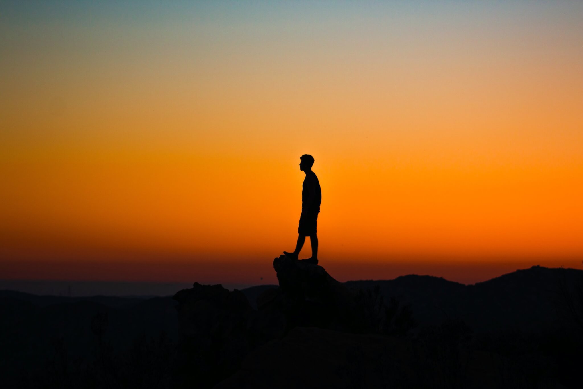 Person alone on cliff at sunset