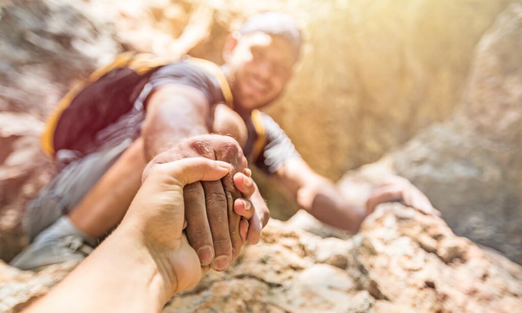 Barmhartige Samaritaan: een man biedt een helpende hand aan een ander tijdens het klimmen
