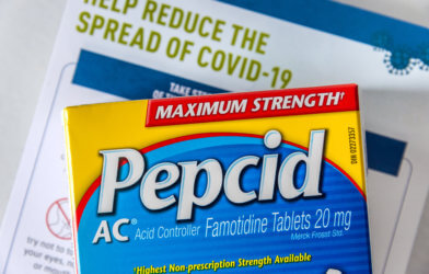 Pepcid AC (Famotidine) antacid medicine in front of a Covid-19 prevention document