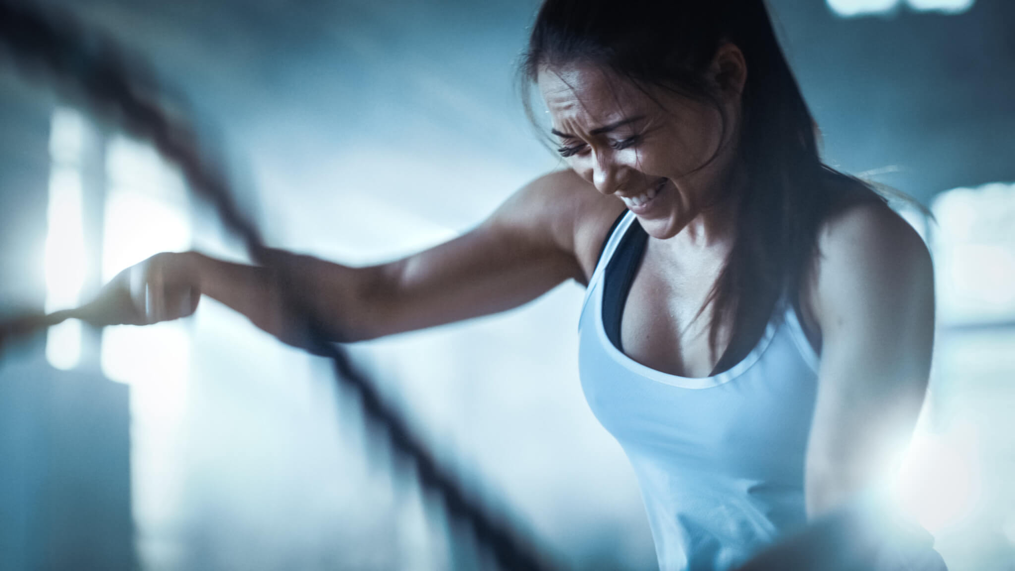 Woman having vigorous workout, strenuous exercise routine with ropes